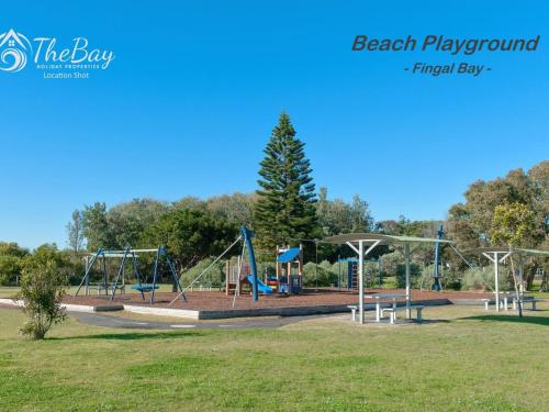 a playground in a park with a tree at Lentara Street No 31 in Fingal Bay