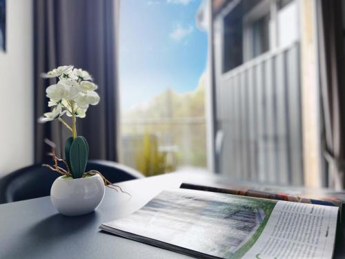 a vase with white flowers on a table with a newspaper at Aux 500 Diables Eco Lodge - Hotel in Chambon-sur-Lac