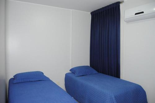 2 bedden in een slaapkamer met blauwe lakens bij Thermas Paradise 2Quartos in Rio Quente