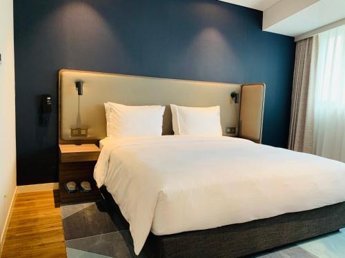 1 dormitorio con 1 cama blanca grande y pared azul en Holiday Inn Express Chongqing Airport Zone, an IHG Hotel en Chongqing