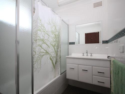 a white bathroom with a sink and a shower at Beachfront 3 Unit 3 of 12 Bundella Ave LC in Lake Cathie