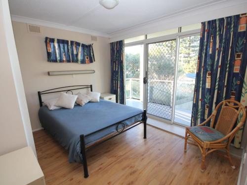 a bedroom with a bed and a balcony at Beachfront 3 Unit 3 of 12 Bundella Ave LC in Lake Cathie
