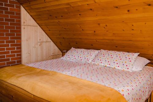 a bed with two pillows on it in a room at Wood house Irena-Počitniška hiša in Bohinj