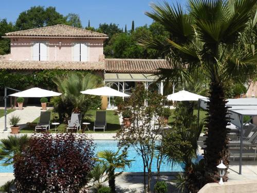 un complexe avec piscine, palmiers et parasols dans l'établissement Lou Relambi, à Bagnols-en-Forêt