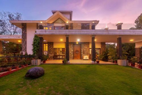 a house with a green lawn in front of it at StayVista's Valencia Villa with Gazebo and Indoor Games in Lonavala
