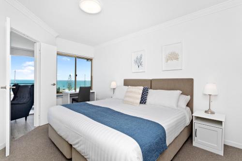 a white bedroom with a bed and a view of the ocean at Suite 310 Sandcastles 3 Bedroom Deluxe in Perth