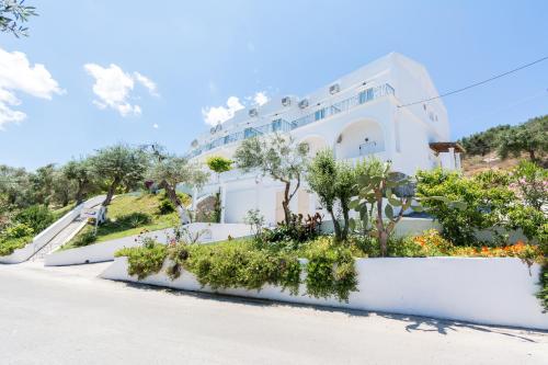 une maison blanche avec des arbres et des plantes sur le côté d'une route dans l'établissement Corfu Aquamarine, à Nótos