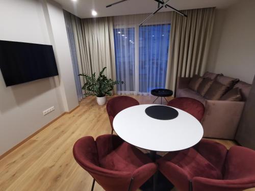 a living room with a white table and red chairs at MyCasa CBD in Vilnius
