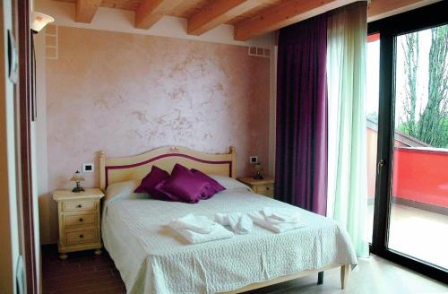 a bedroom with a bed with purple pillows and a window at Agriturismo Aver in Villafranca di Verona