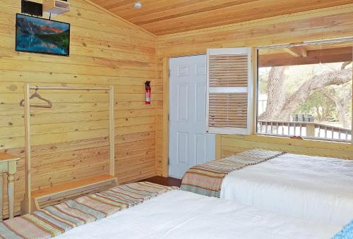 Wimberley Log Cabins Resort and Suites- Unit 8 في ويمبيرلي: غرفة نوم بسريرين في كابينة خشب