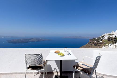 - une table et des chaises blanches avec vue sur l'océan dans l'établissement Spitia Tzitzi, à Imerovigli
