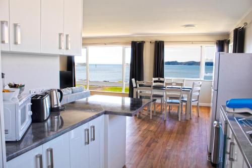 a kitchen and dining room with a view of the ocean at Rehutai Beach House in Paihia