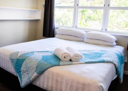 een bed met handdoeken en een raam bij Rehutai Beach House in Paihia