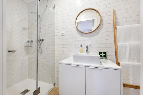 uma casa de banho branca com um lavatório e um espelho em RG Studio em Faro