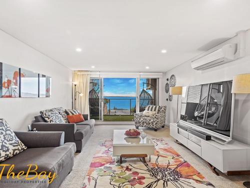 a living room with a couch and a tv at The Shoal 401 in Shoal Bay