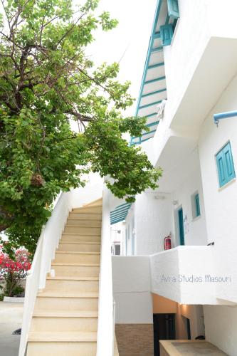 a staircase leading up to a white building with a tree at Avra Studios in Masouri