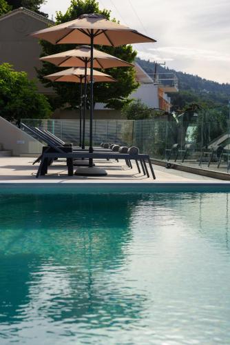 a pool with chairs and an umbrella and some water at Villa Alexandra in Boukari