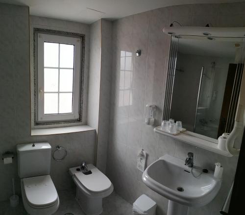 a bathroom with a white toilet and a sink at HOTEL LA CAMPANA in Llanera