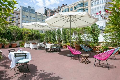 a patio area with chairs, tables and umbrellas at Mihlton Barcelona Boutique B&B in Barcelona