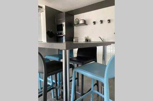 une cuisine avec un comptoir et quelques tabourets de bar bleus dans l'établissement Le gîte de Malot ****, à Saint-Romans