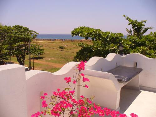 una cerca blanca con un banco y flores rosas en Seagreen Guesthouse, en Galle