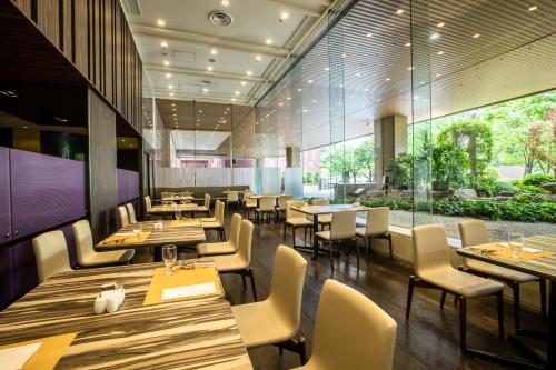 a restaurant with wooden tables and chairs and windows at ANA Crowne Plaza Hiroshima by IHG in Hiroshima