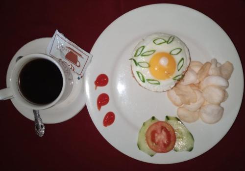 a plate of food with an egg and a cup of coffee at Ganga Hotel & Apartment in Denpasar