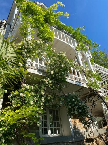 a white building with flowering trees in front of it at Villa Ananda Huo in Saint-Cloud