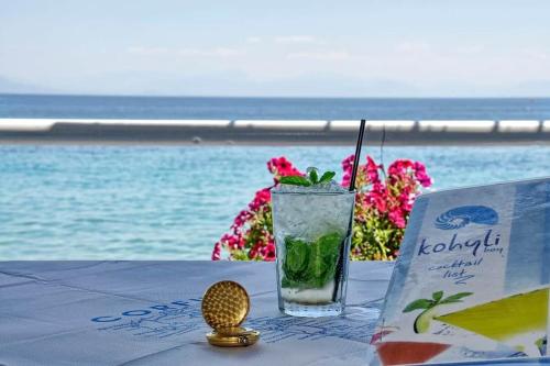 una bebida sentada en una mesa con el océano en el fondo en IONIAN MARE, en Agios Ioannis Peristerion