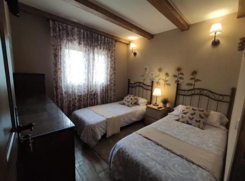 a bedroom with two beds and a window at LAS 4 ESTACIONES - Rascafría in Rascafría