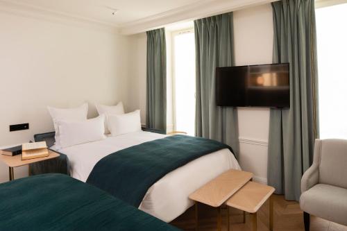 a hotel room with a large bed and a chair at Hotel Louvre Montana in Paris
