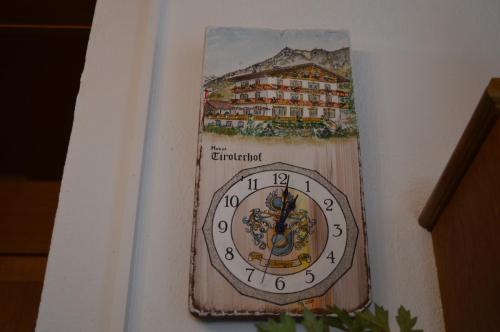 a clock on a wall with a picture of a hotel at Tirolerhof in Lermoos