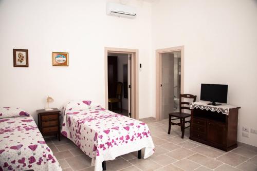 una camera da letto con due letti e una TV a schermo piatto di Trulli Donna Isabella 2 a Locorotondo