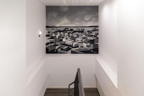 a painting hanging on a wall in a stair case at Hotel Cidade de Olhão in Olhão