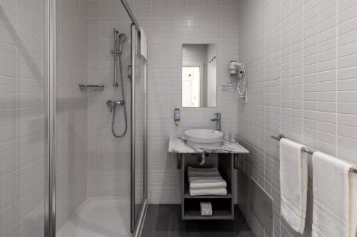 uma casa de banho branca com um lavatório e um chuveiro em Hotel Cidade de Olhão em Olhão