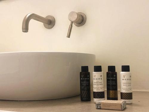 a bathroom sink with three bottles of cosmetics on a counter at Thera Incognita Studios in Perissa