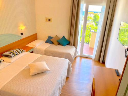 a hotel room with two beds and a balcony at Hotel President in Cattolica