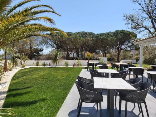 un patio con tavoli, sedie e prato di Hotel Mas des Lys a Saintes-Maries-de-la-Mer