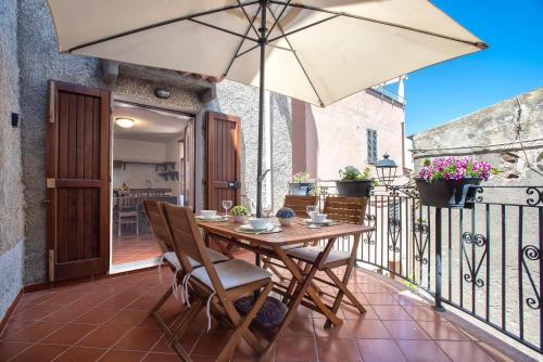 a patio with a table and an umbrella on a balcony at Esclusiva Dimora Storica nel cuore del Borgo Medievale---- Exclusive Historical House inside the Medieval Village in Castelsardo