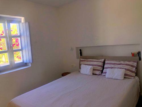 1 dormitorio con 1 cama blanca y ventana en Thera Incognita Studios, en Perissa