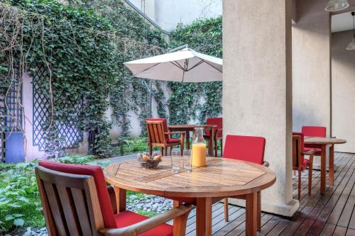 - une table en bois avec des chaises et un parasol sur la terrasse dans l'établissement Citadines Montparnasse Paris, à Paris