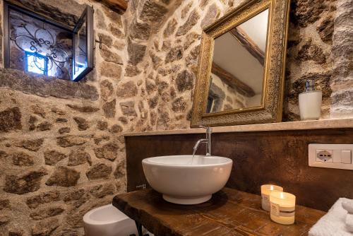 a stone bathroom with a sink and a mirror at Esclusiva Dimora Storica nel cuore del Borgo Medievale---- Exclusive Historical House inside the Medieval Village in Castelsardo