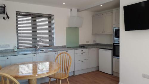a kitchen with white cabinets and a wooden table at Courtbrook Farm Apartments in Exeter