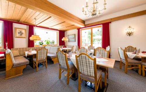 a dining room with tables and chairs and windows at Tirolerhof in Lermoos