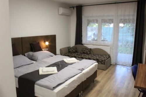 1 dormitorio con 2 camas, sofá y ventana en Czermann Holiday Inn, en Oroszlány