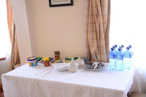 een witte tafel met flessen water erop bij New Green Pastures Guest House in Eldoret