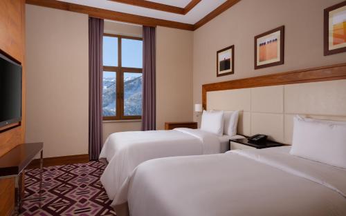 a hotel room with two beds and a flat screen tv at Mövenpick Hotel Krasnaya Polyana in Estosadok