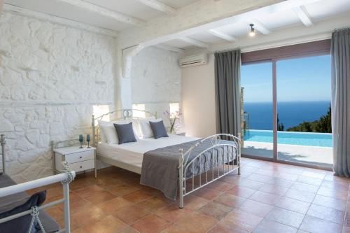 a bedroom with a bed and a view of the ocean at Acquaterra Villas in Tsoukalades