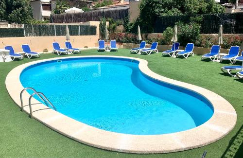 a swimming pool with blue chairs and chairs in a yard at Apartamentos Las Palmeras in Palmanova