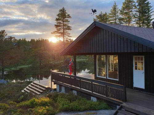 a house with the sun setting in the background at Solhytta Fantastisk beliggenhet! Hytte til leie på Skrim! in Kongsberg